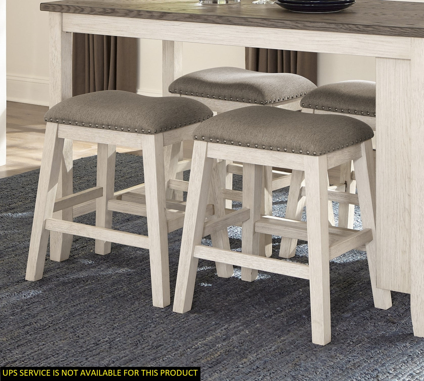 Four gray upholstered counter stools with nailhead trim and light wood legs