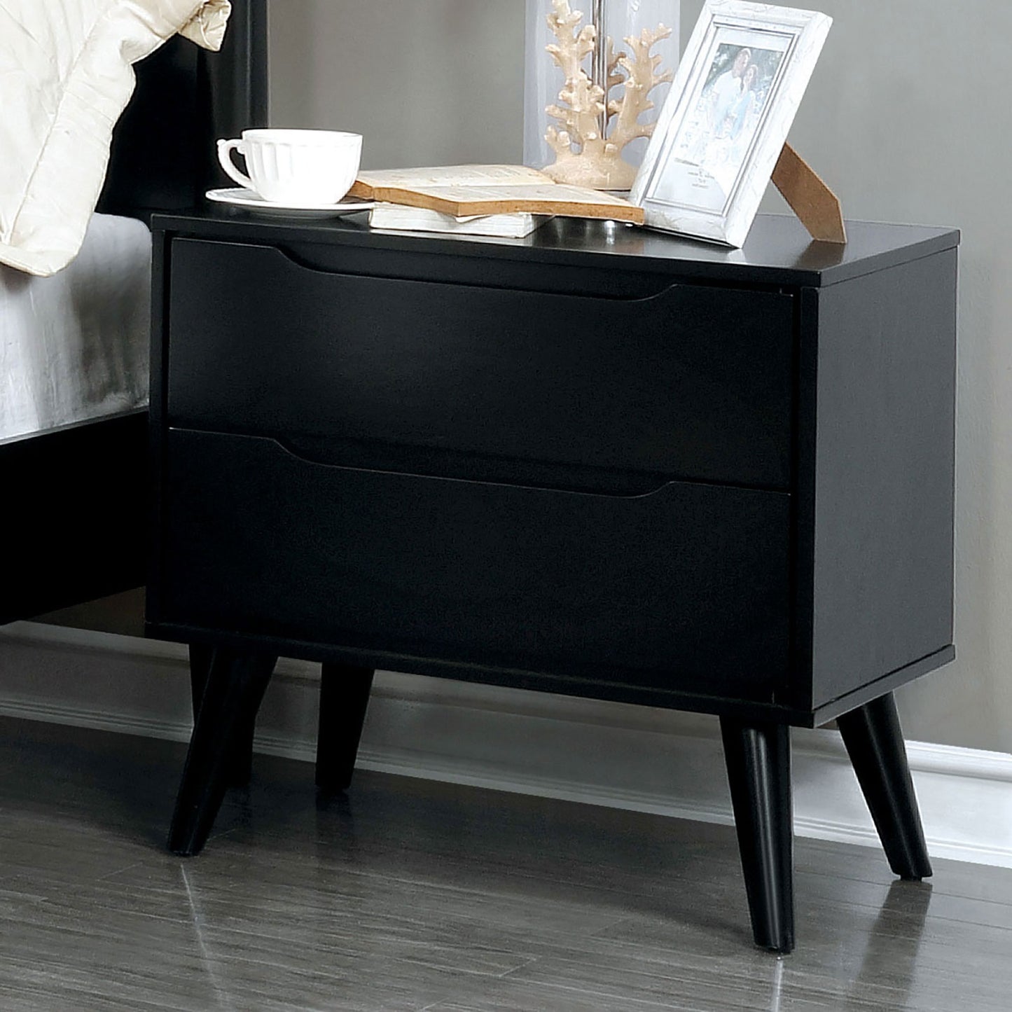 Sleek black twodrawer nightstand with tapered legs and modern carved drawer fronts