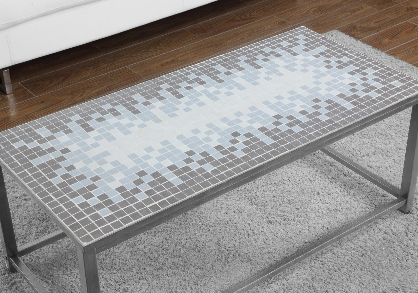 Rectangular coffee table with mosaic tile top in gray and blue hues on a shag rug
