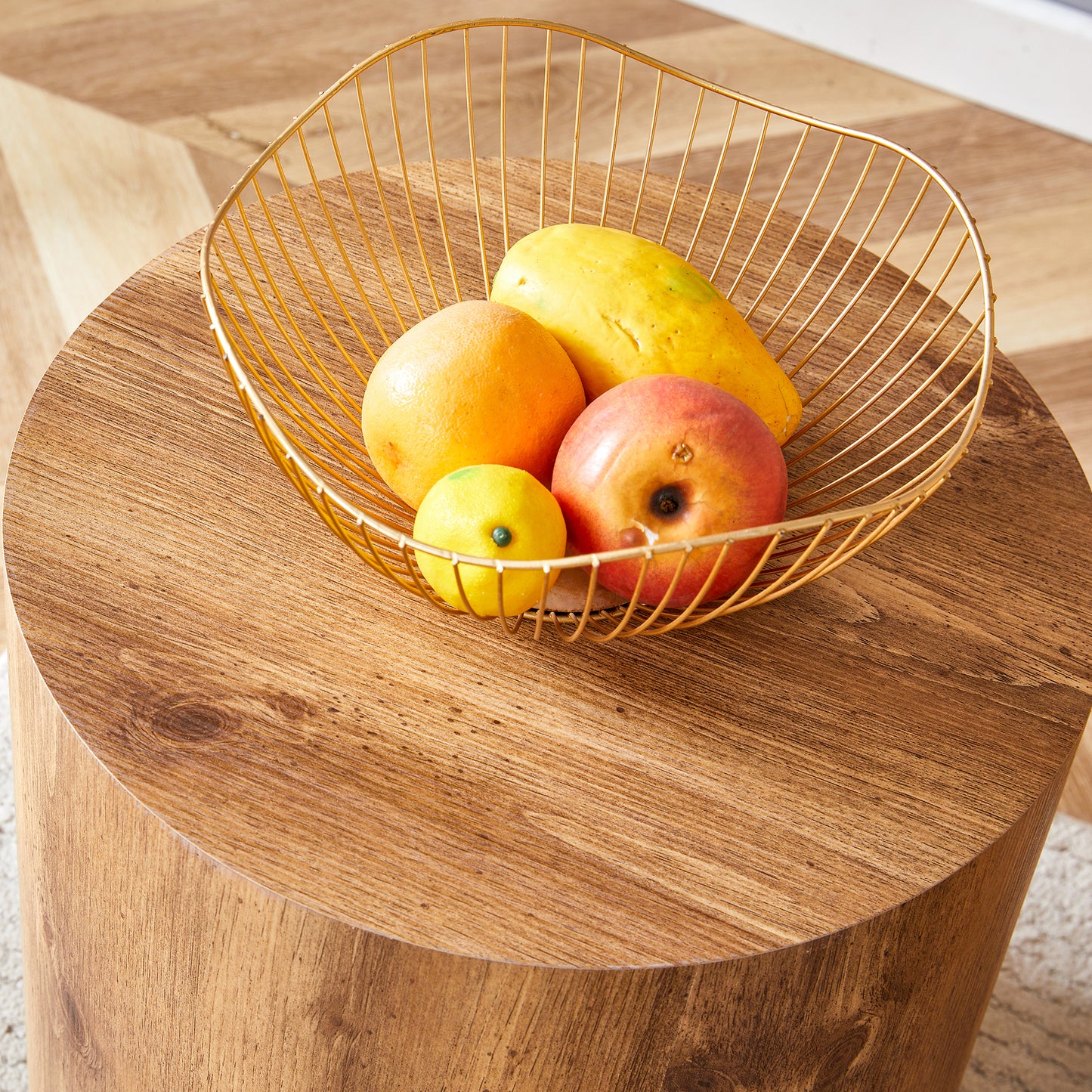 Gold wire fruit basket holding apple orange papaya and lemon on wooden table