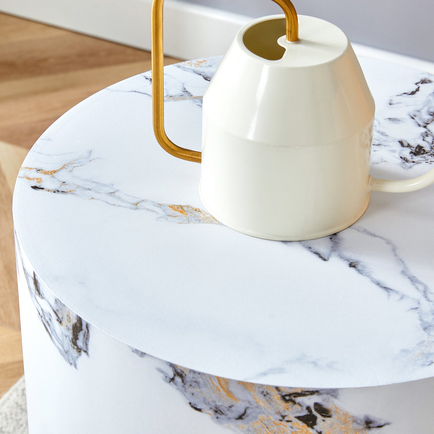 Cream metal watering can with gold handle on white marble side table