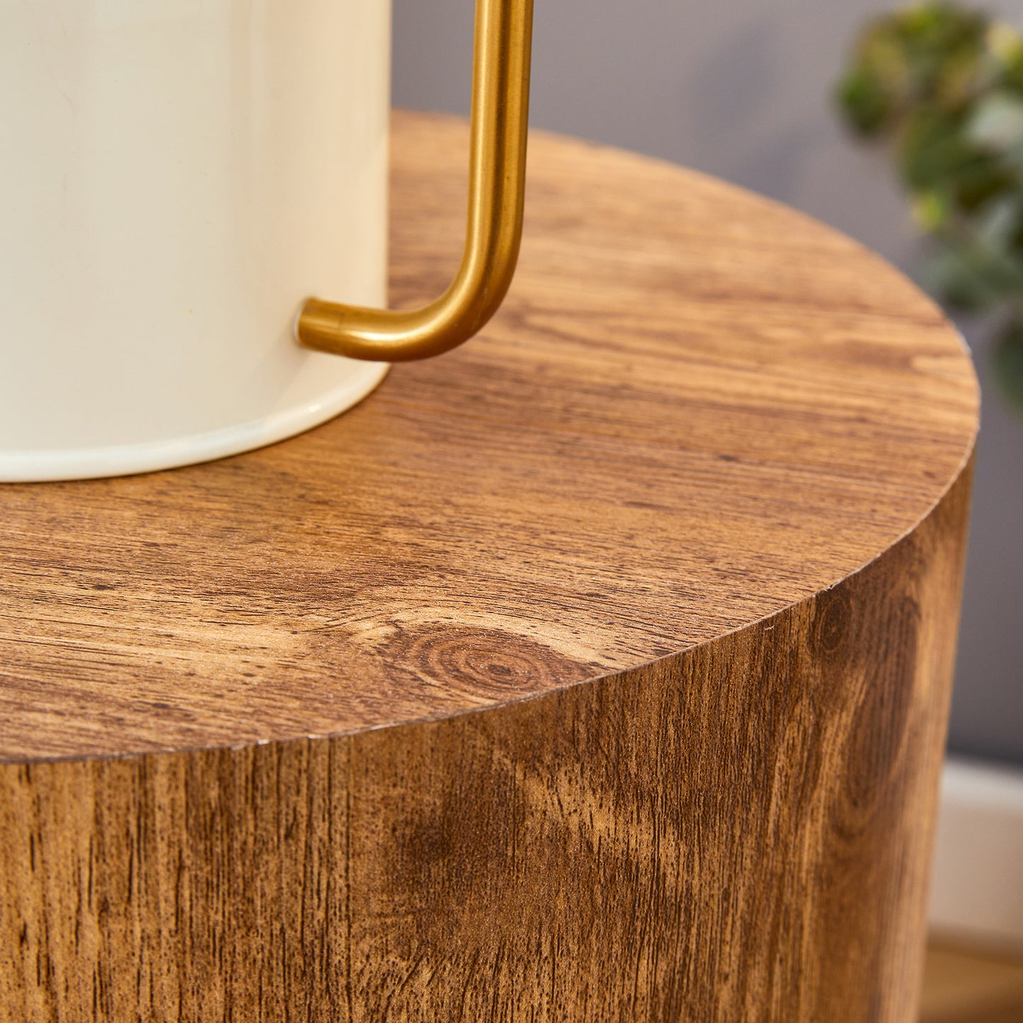 Cream ceramic mug with gold handle on a rustic wood side table