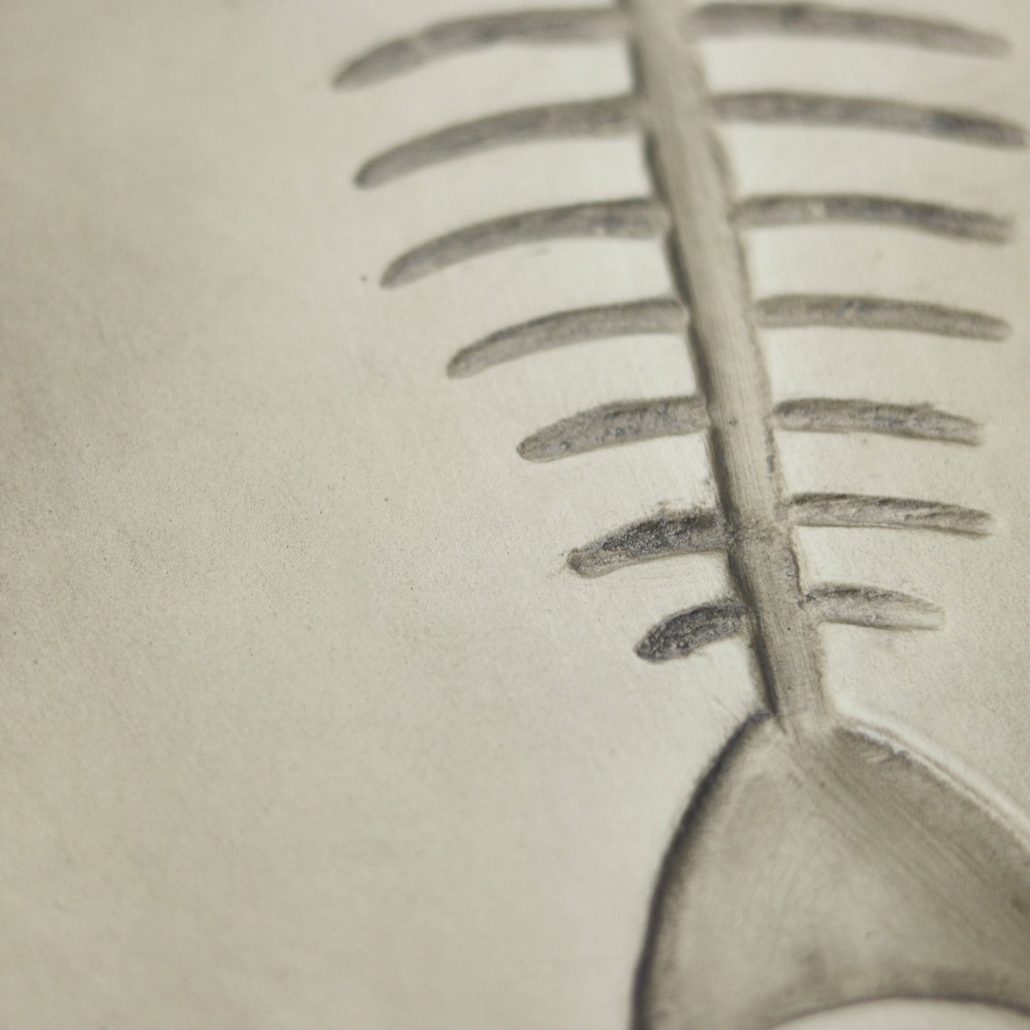 Closeup of a grey ceramic fishbone embossed design on a textured surface