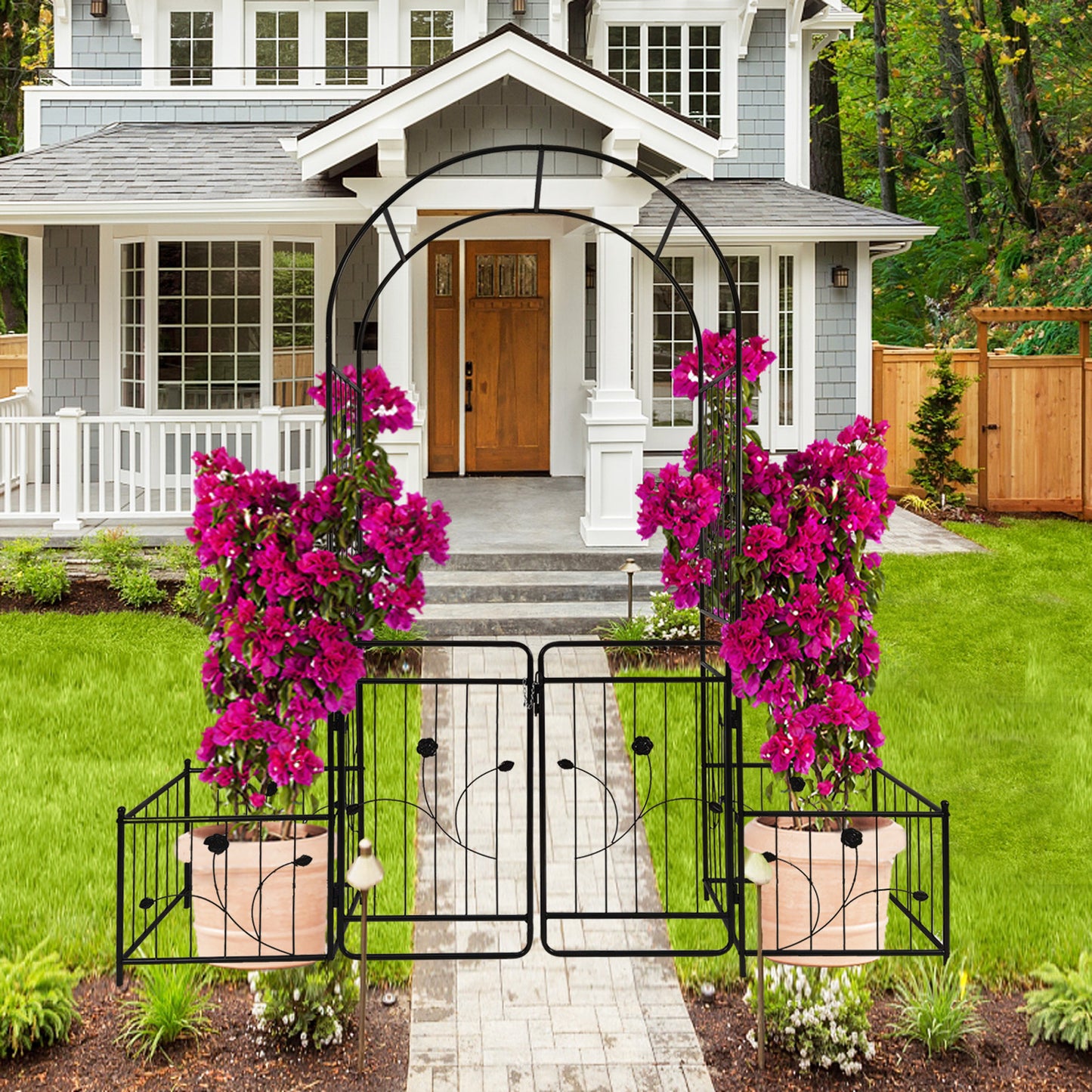 Black wrought iron garden archway with double gates and floral accents framing a walkway to a home entrance