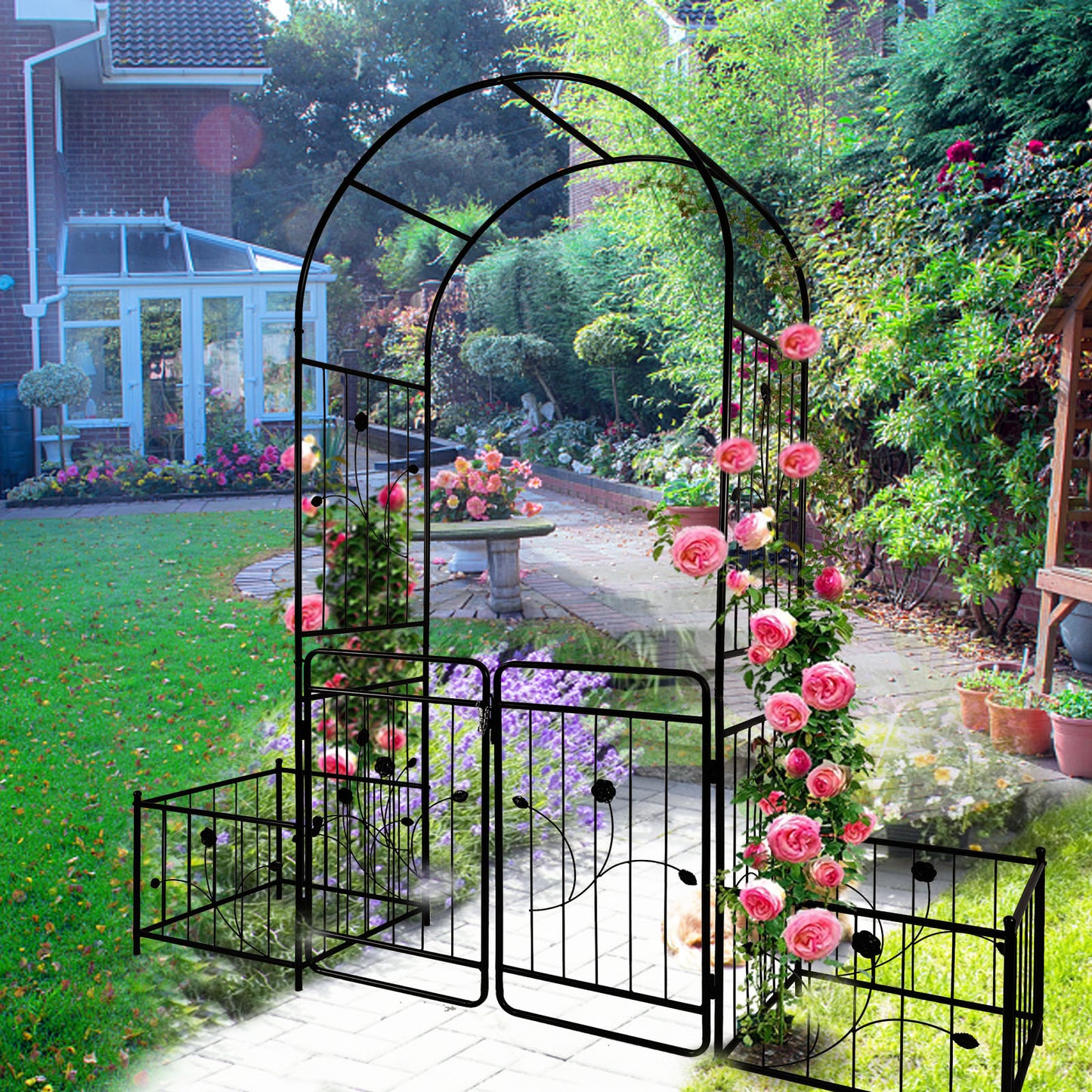 Black metal garden archway with climbing pink roses and decorative gates