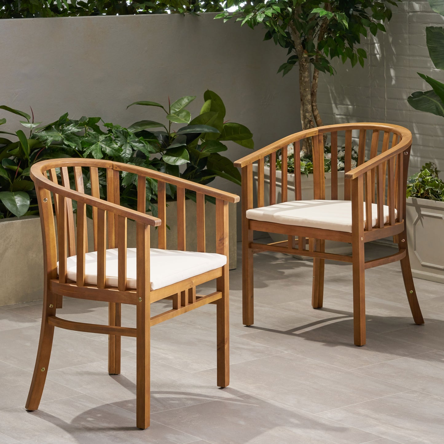 Two wooden outdoor chairs with white cushions in a garden setting