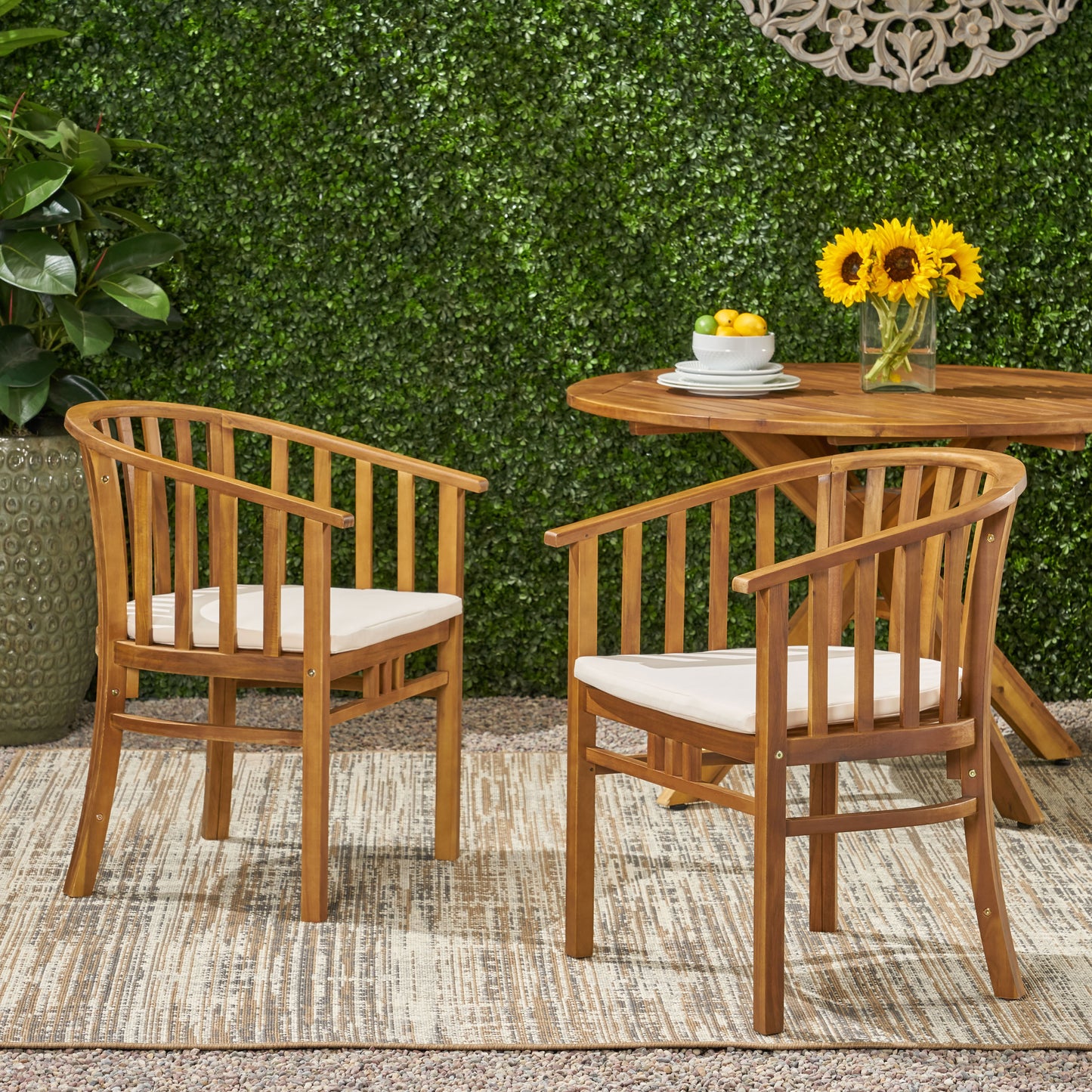 Two wooden outdoor dining chairs with beige cushions set on a textured rug