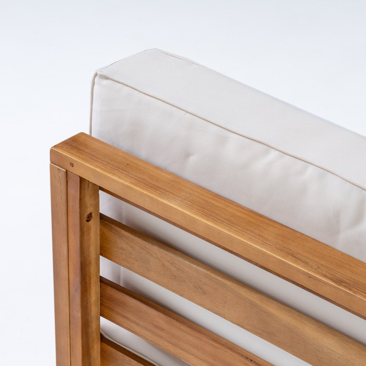 Closeup of natural wood patio chair armrest with offwhite cushion