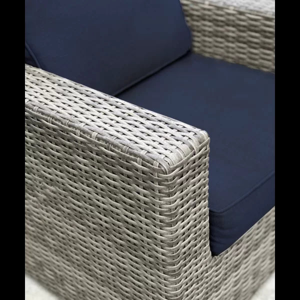 Closeup of grey wicker outdoor sofa armrest with navy blue cushion