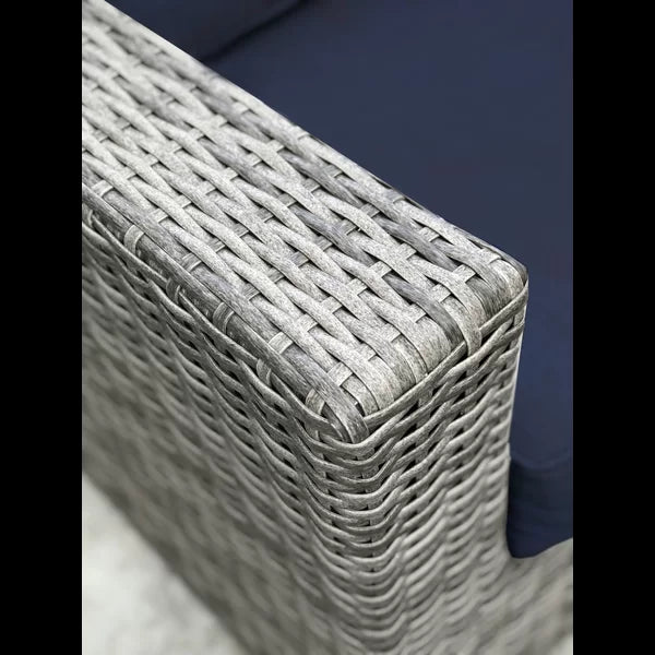 Closeup of a grey wicker chair armrest with navy blue cushion perfect for outdoor patio furniture
