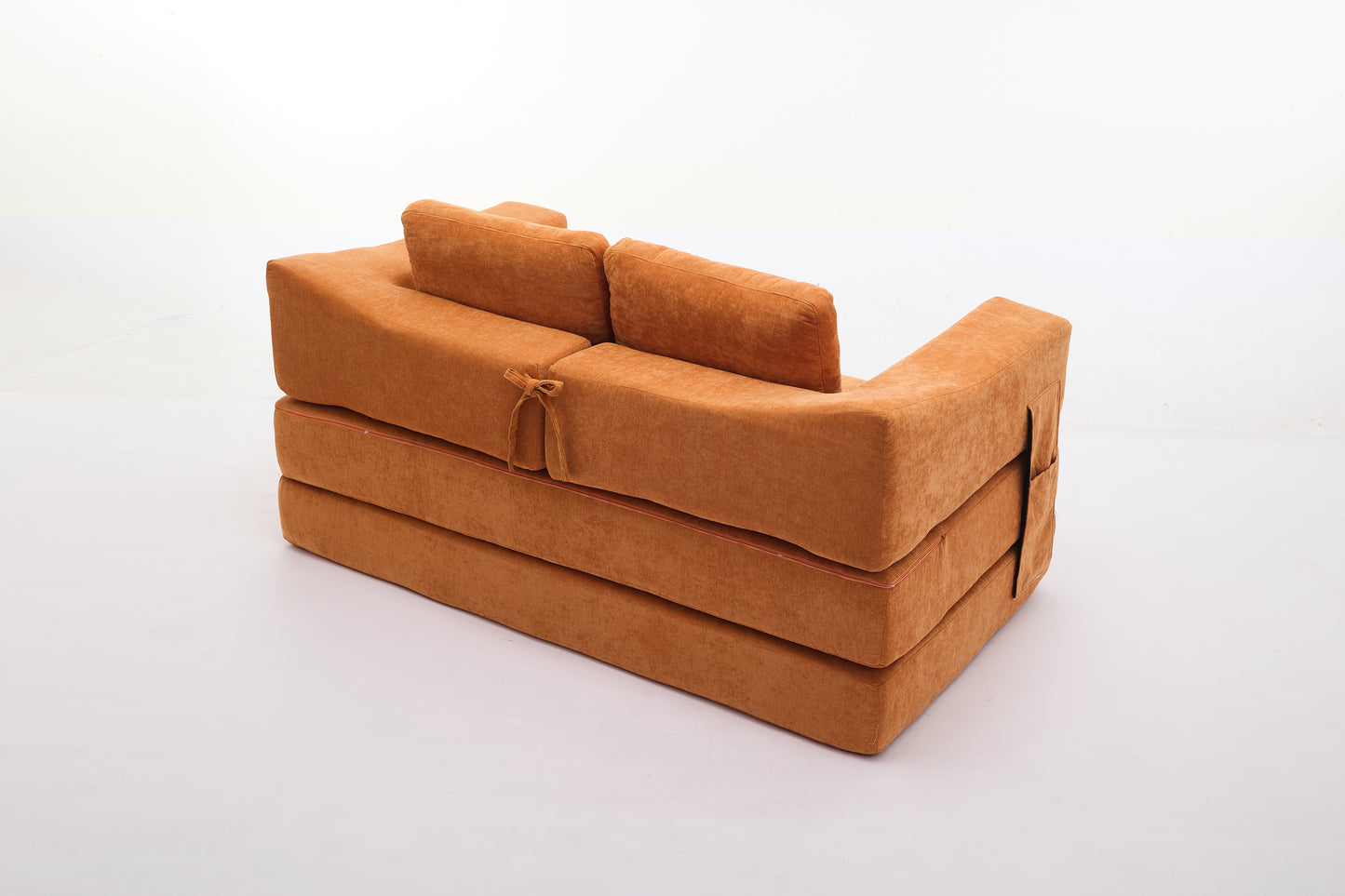 Orange futon sofa bed with plush fabric and tie details perfect for small spaces