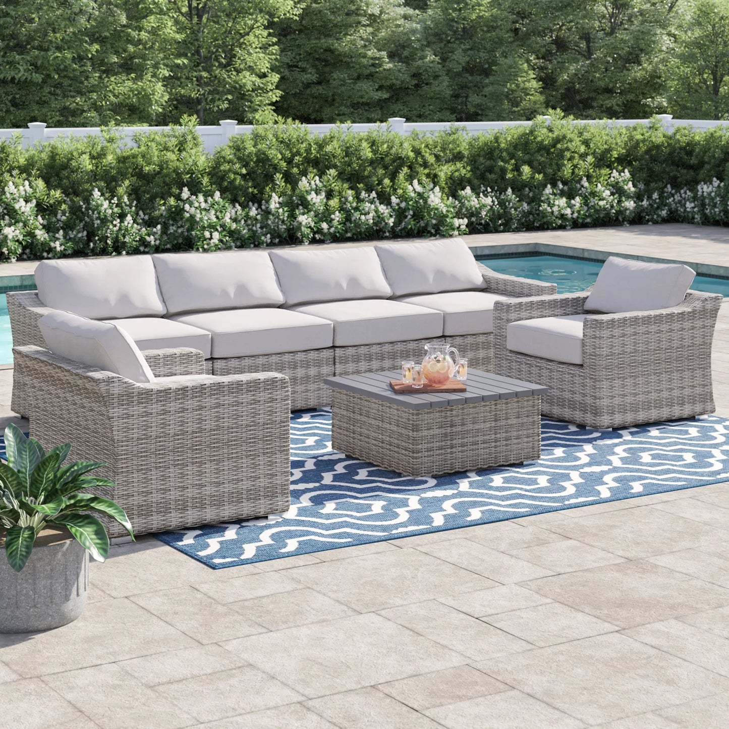 Gray wicker outdoor sectional sofa with plush white cushions and a matching coffee table