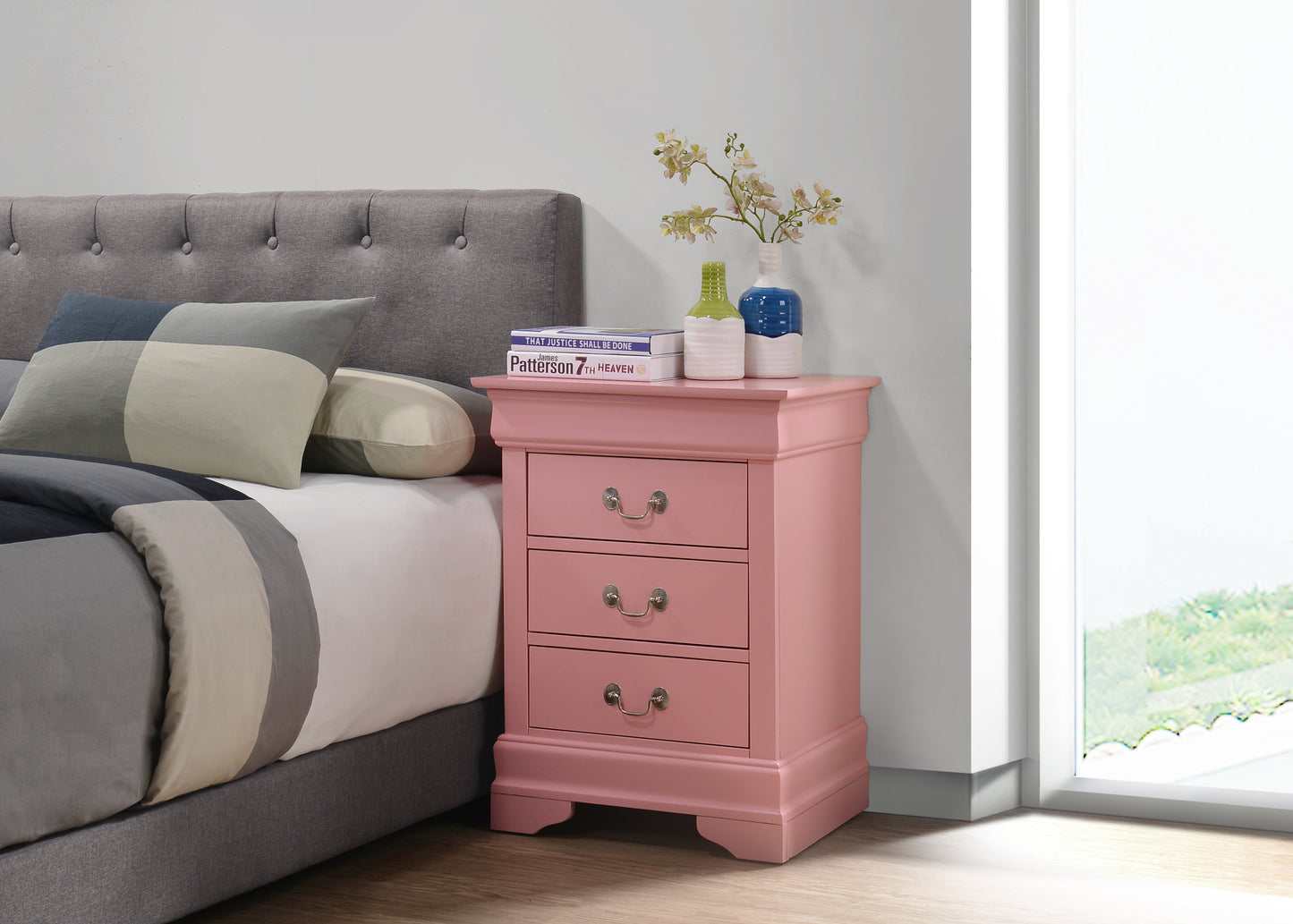 Dusty rose bedside table with three drawers and ornate hardware