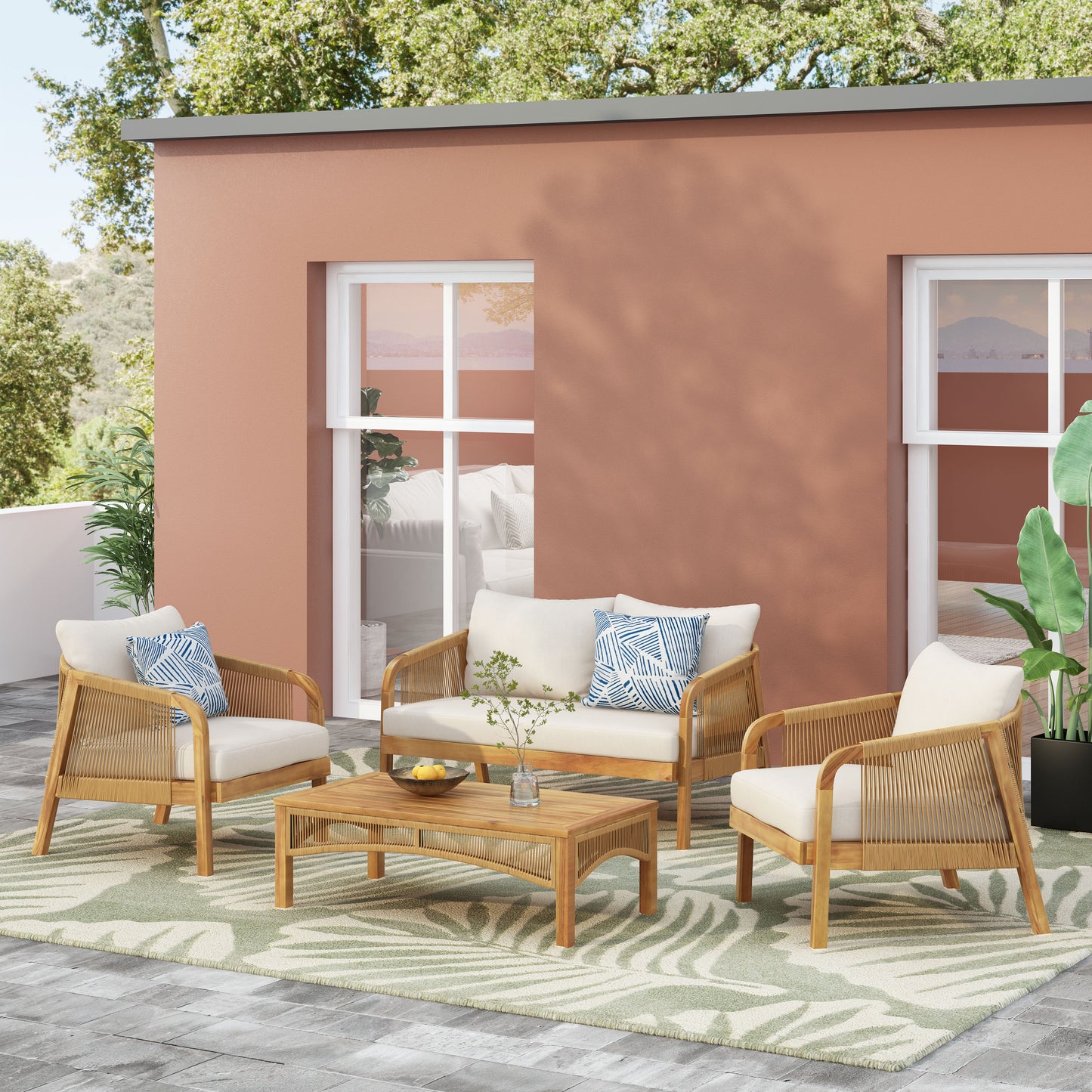 Woven rattan patio set with cream cushions and blue patterned pillows