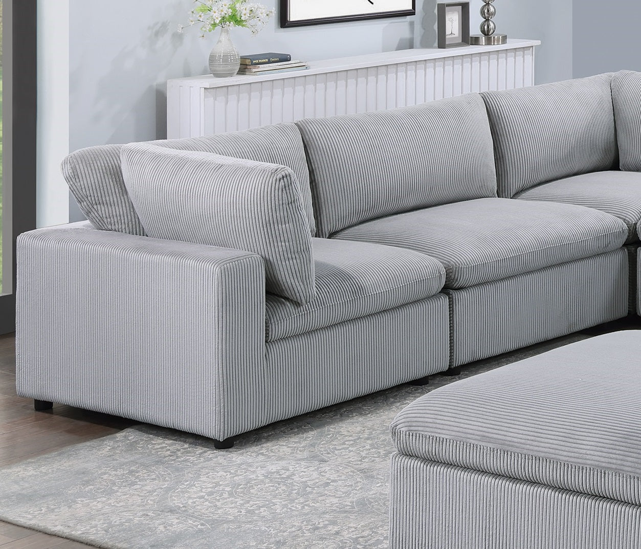 Gray corduroy sectional sofa with plush cushions and a matching ottoman