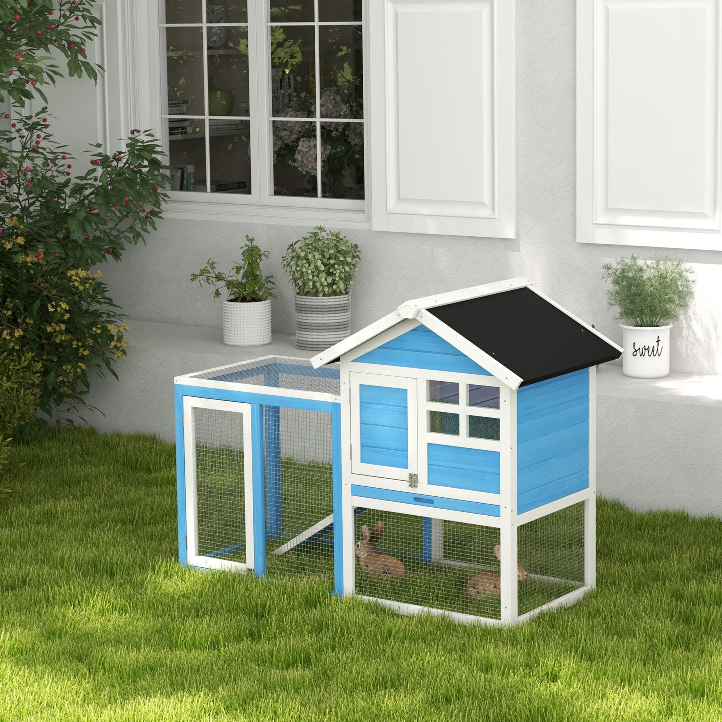 Blue and white outdoor rabbit hutch with two compartments on green grass