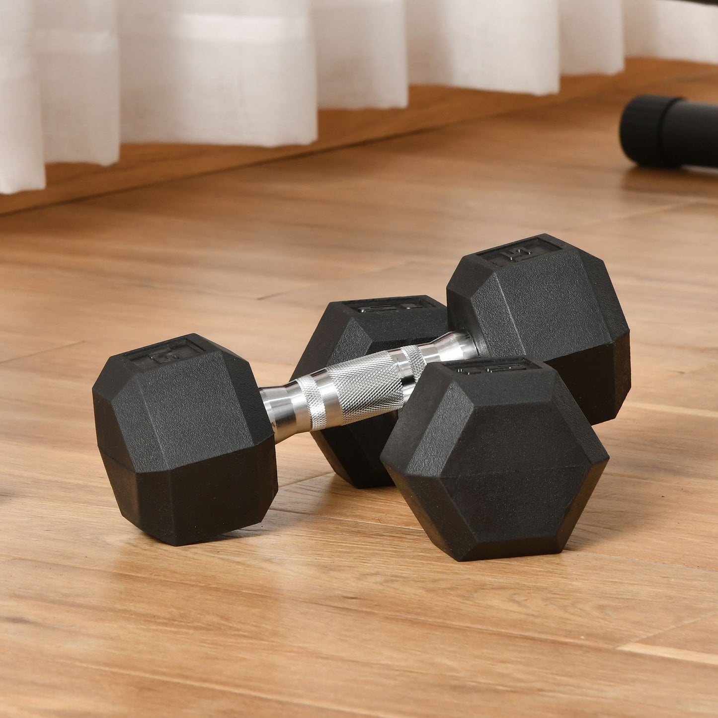 Two black hex dumbbells with chrome handles on a wooden floor
