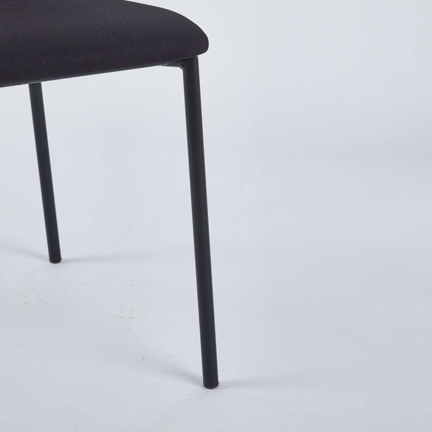 Textured black fabric seat and thin black metal leg of a modern chair