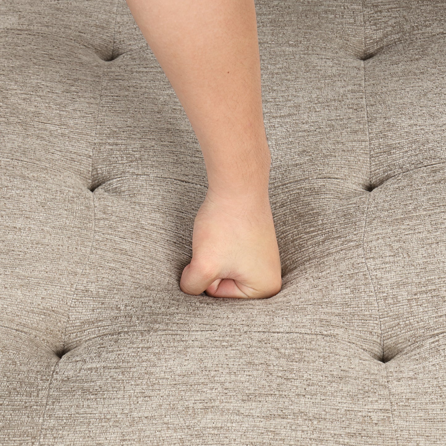 Hand pressing into tufted beige textured fabric sofa for comfort test