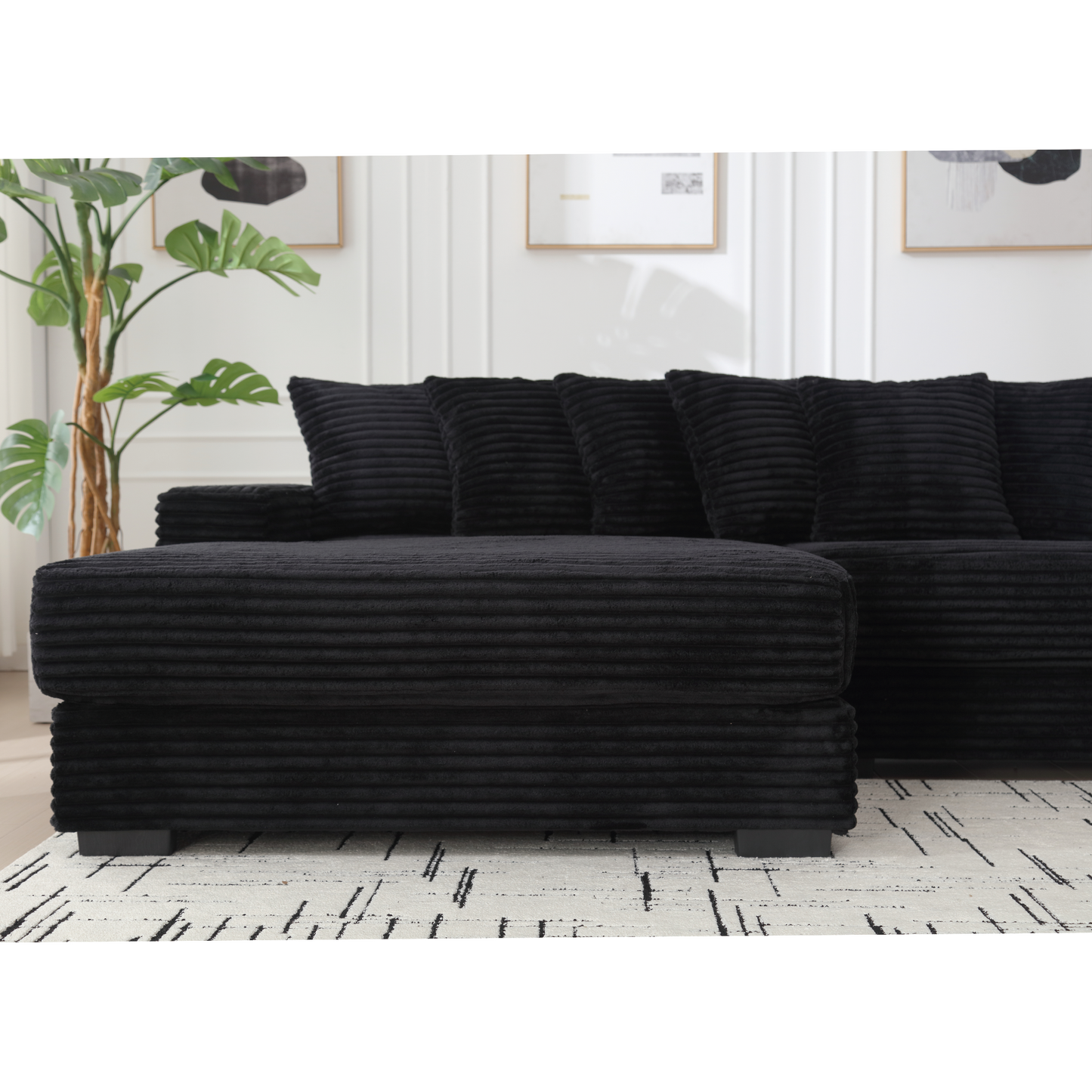 Black corduroy sectional sofa with plush cushions and matching ottoman for a modern living room