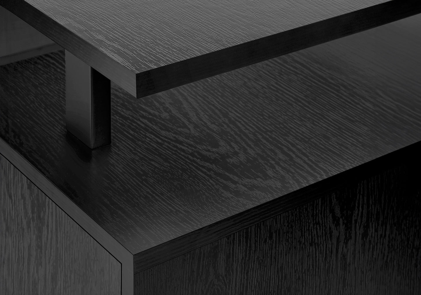 Closeup of a black wood grain desk surface with a metallic leg detail