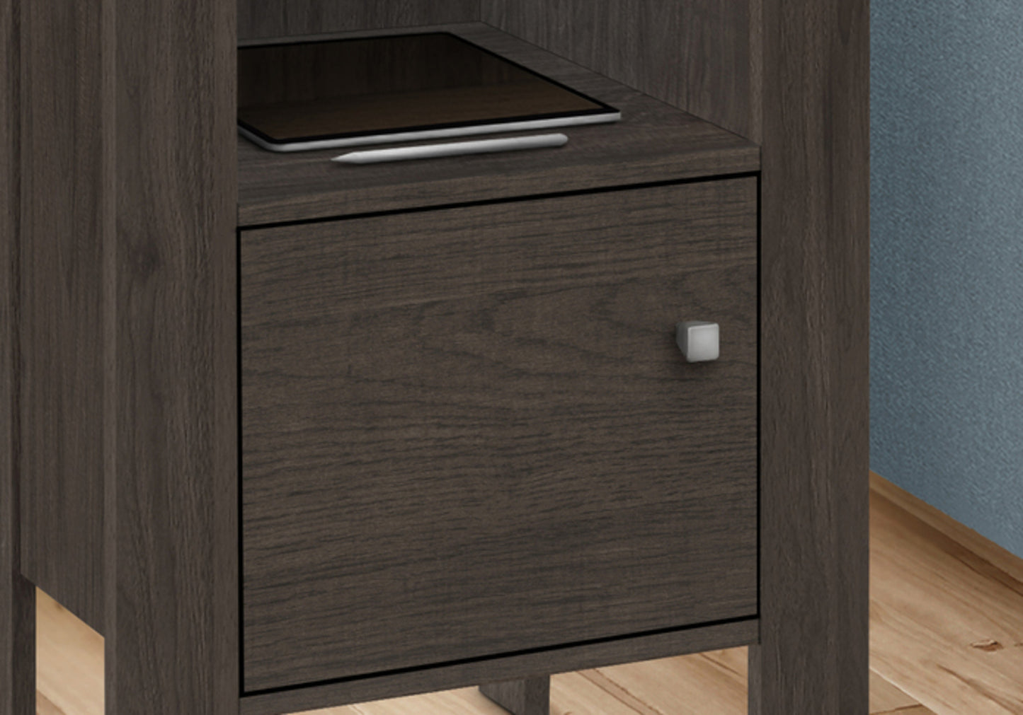 Dark wood nightstand drawer with a silver square pull holding a tablet