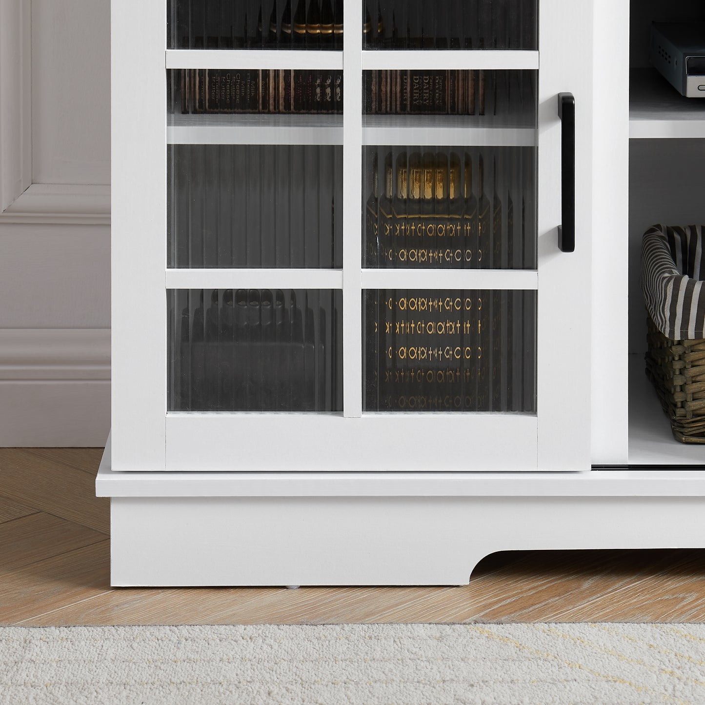White cabinet with fluted glass doors displaying decorative antique books for storage