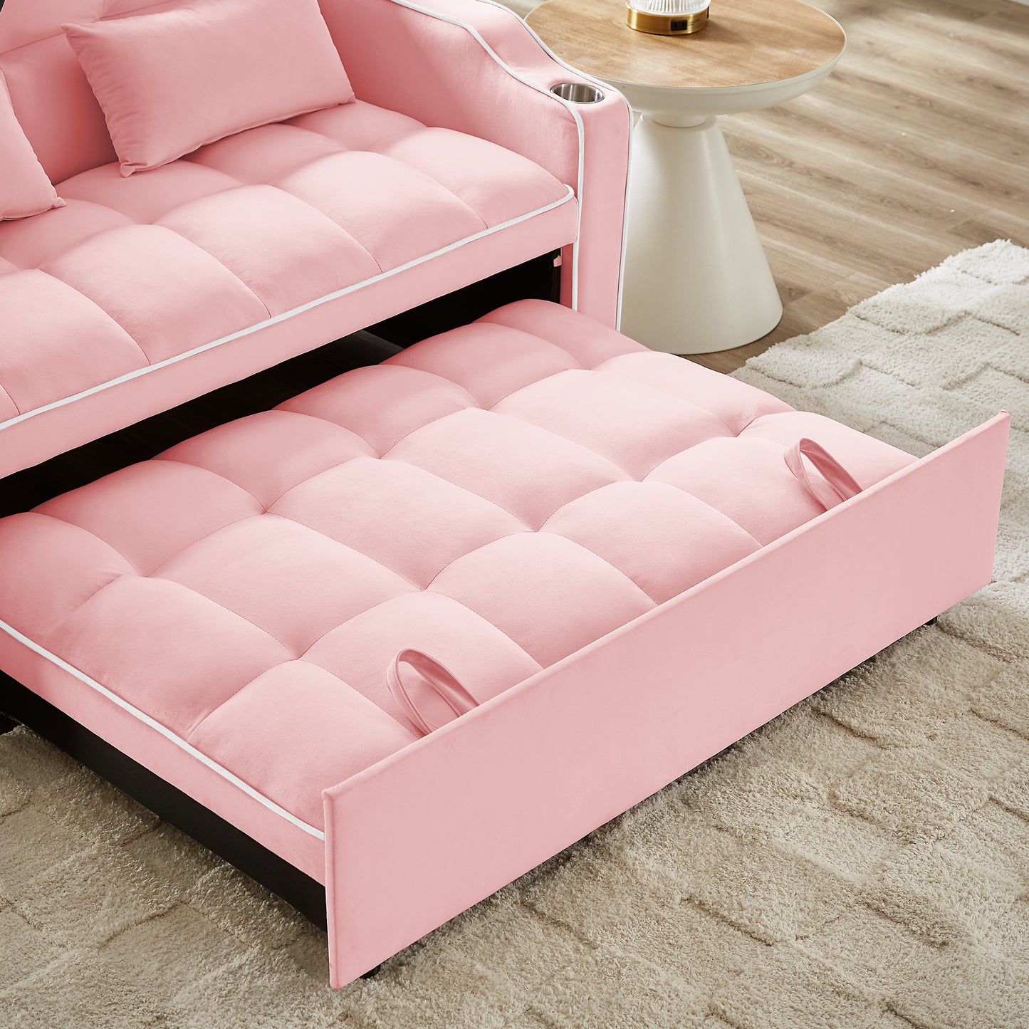 Plush pink velvet sofa bed with pullout mattress and cup holders perfect for small spaces