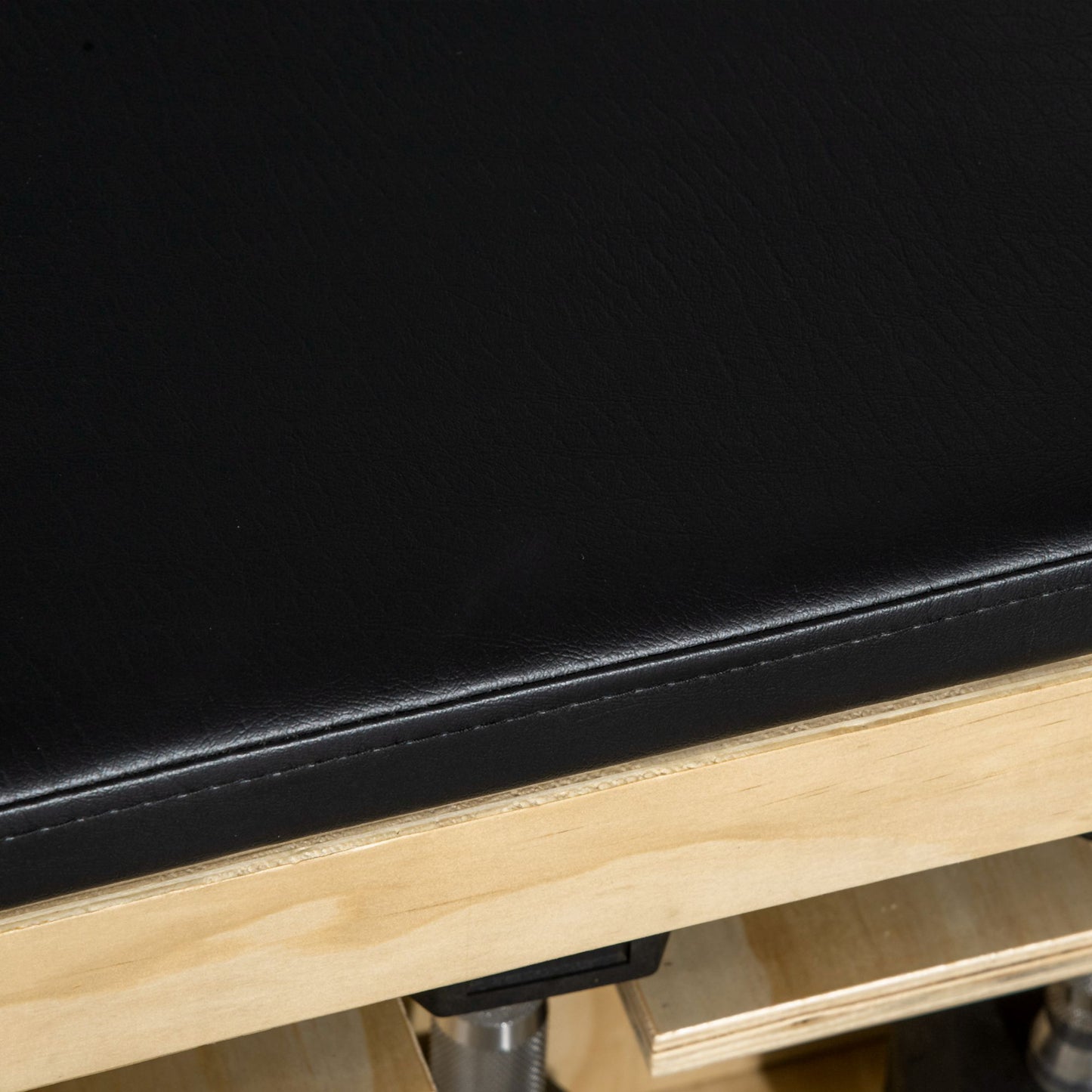 Black leather upholstered pilates reformer carriage with wood frame detail