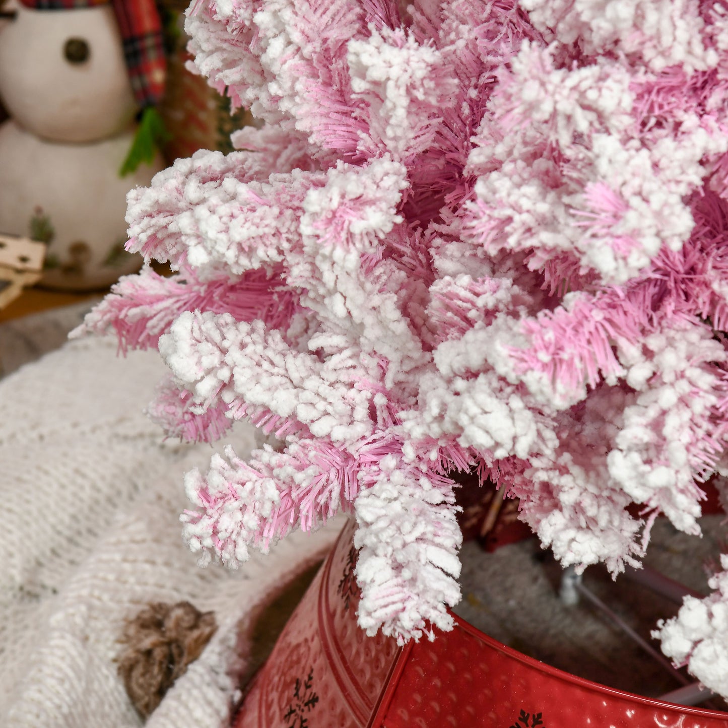 Flocked pink artificial Christmas tree with white tips in a red bucket