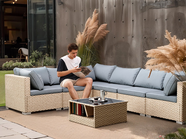 Sectional rattan outdoor sofa with light blue cushions and a glasstop coffee table
