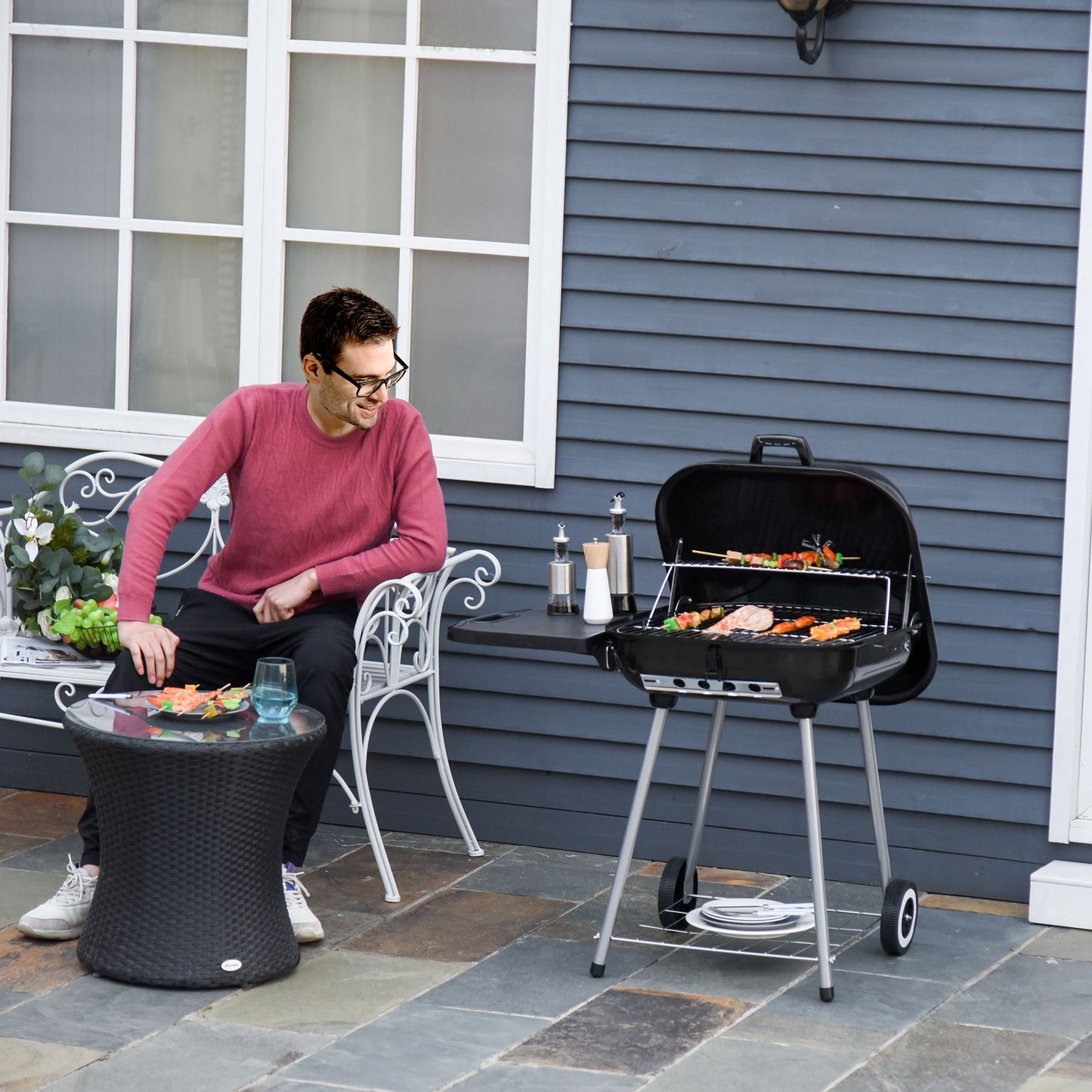 Black charcoal kettle grill with meat skewers cooking on grate