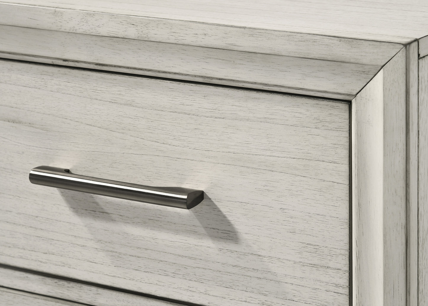 Closeup of a light gray distressed wood dresser drawer with a brushed nickel handle