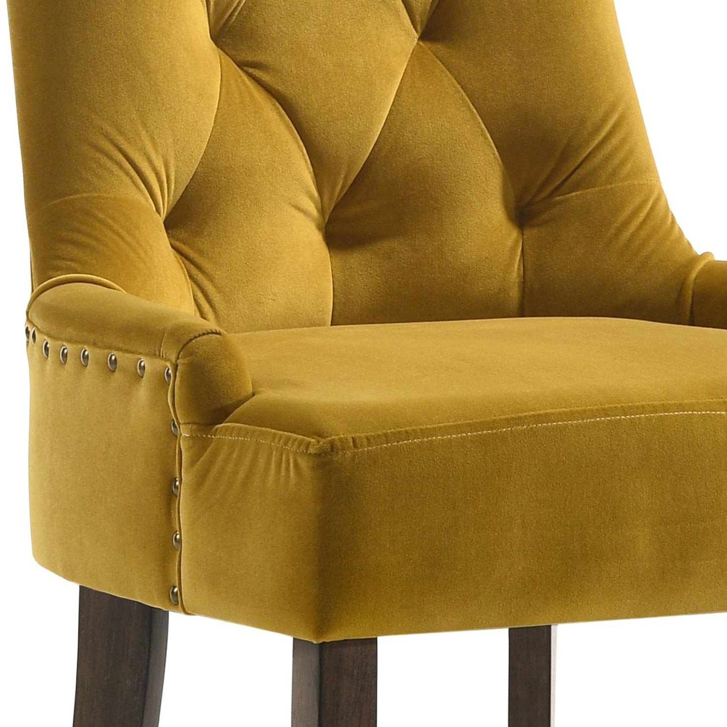 Closeup of a mustard yellow velvet bar stool featuring tufted backrest and nailhead trim accents
