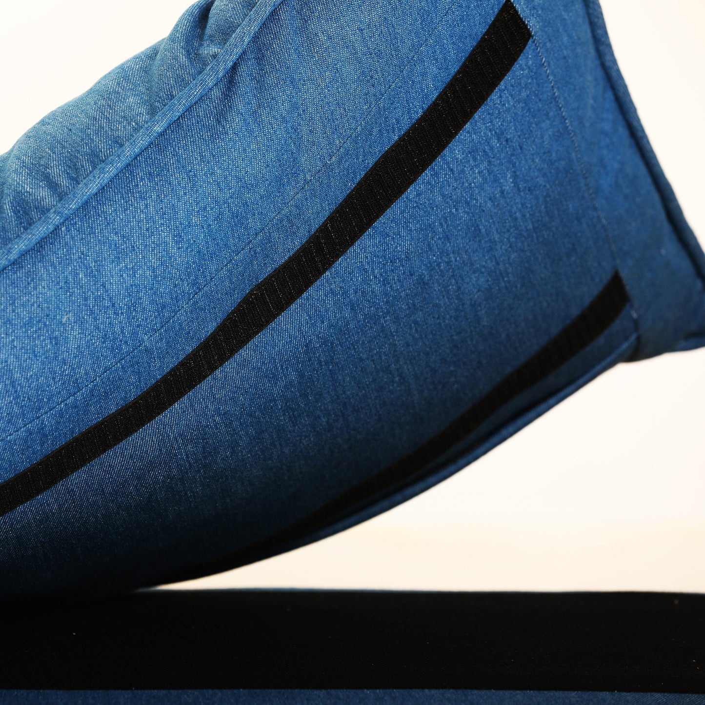 Closeup of a blue denim pillow with black stripe detail perfect for casual decor