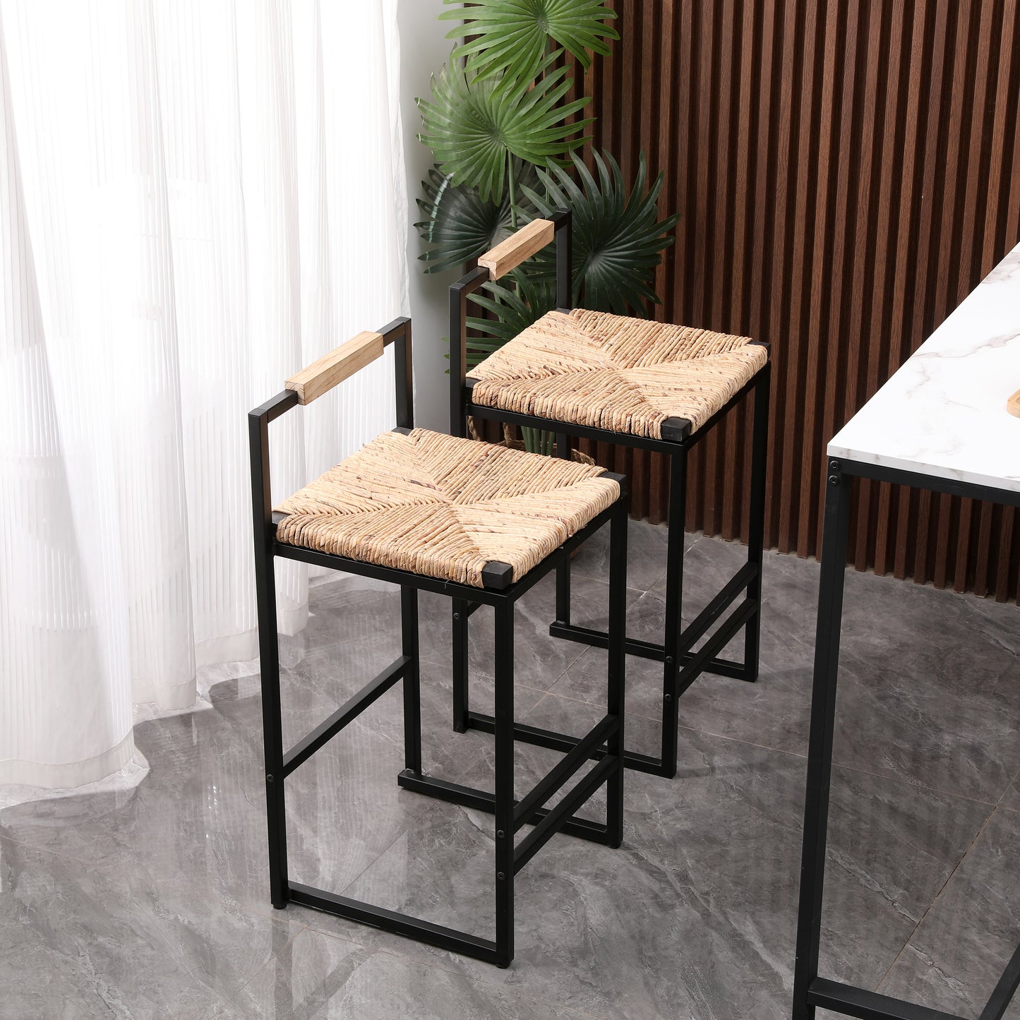 Two black metal bar stools with natural woven seats and wooden armrests sit near a marbletopped table