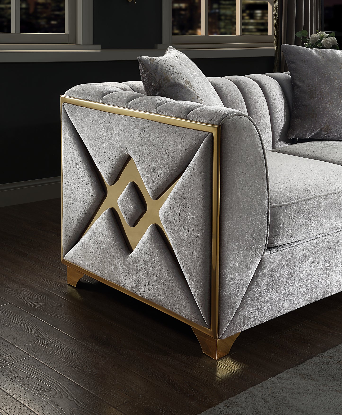 Gray velvet sofa with gold geometric trim and tufted accents