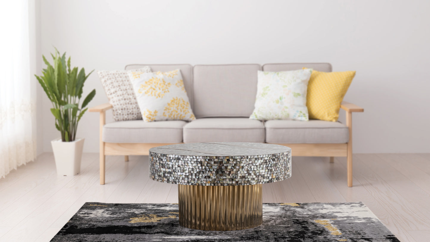 Circular mosaic coffee table with a fluted gold base on a grey and gold abstract rug