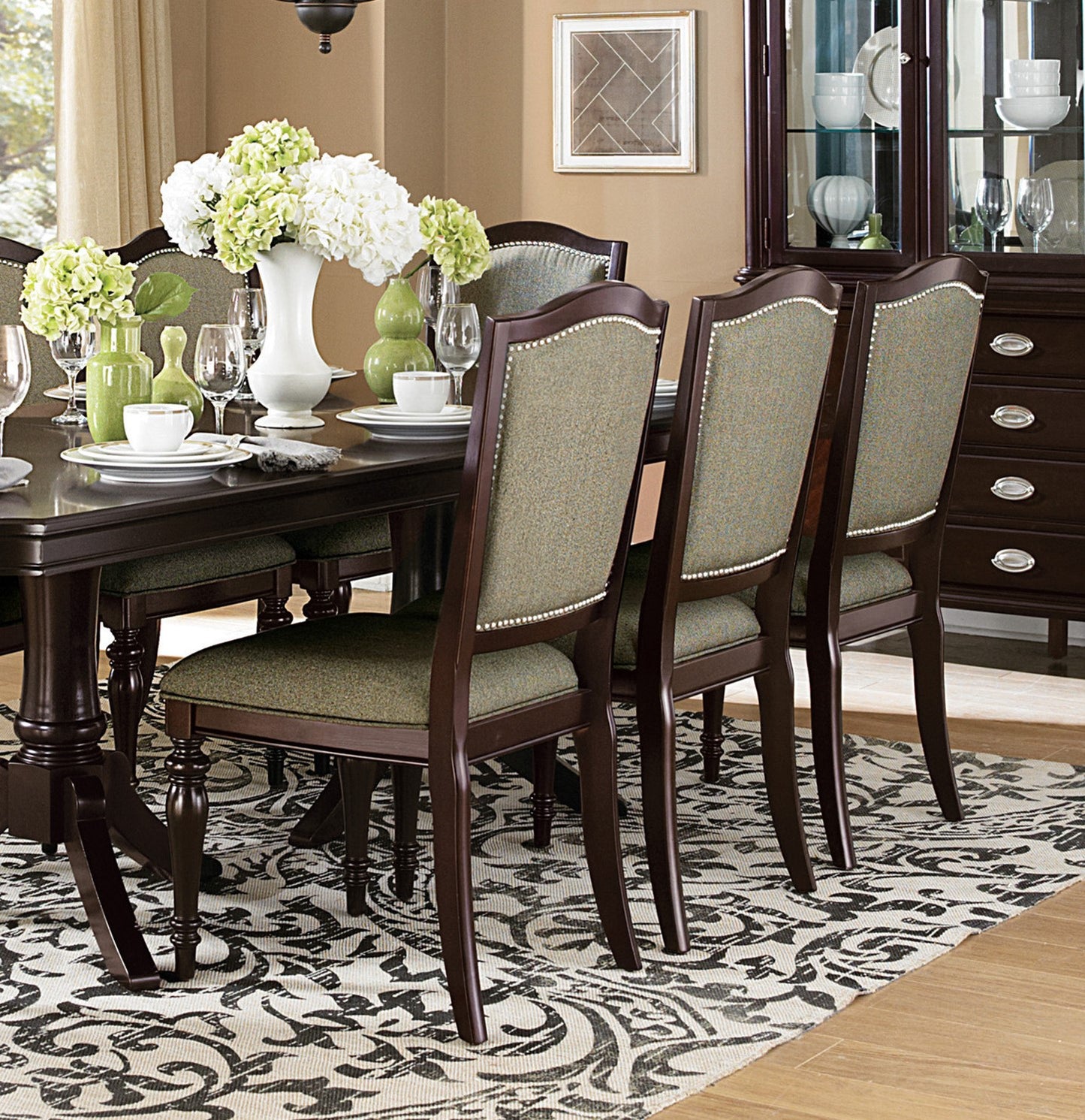 Dark wood dining chairs upholstered in textured green fabric with nailhead trim
