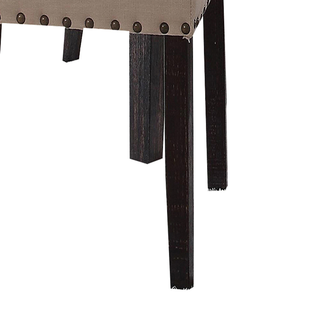 Tufted beige fabric seat with dark wood legs and antique brass nailhead trim accent