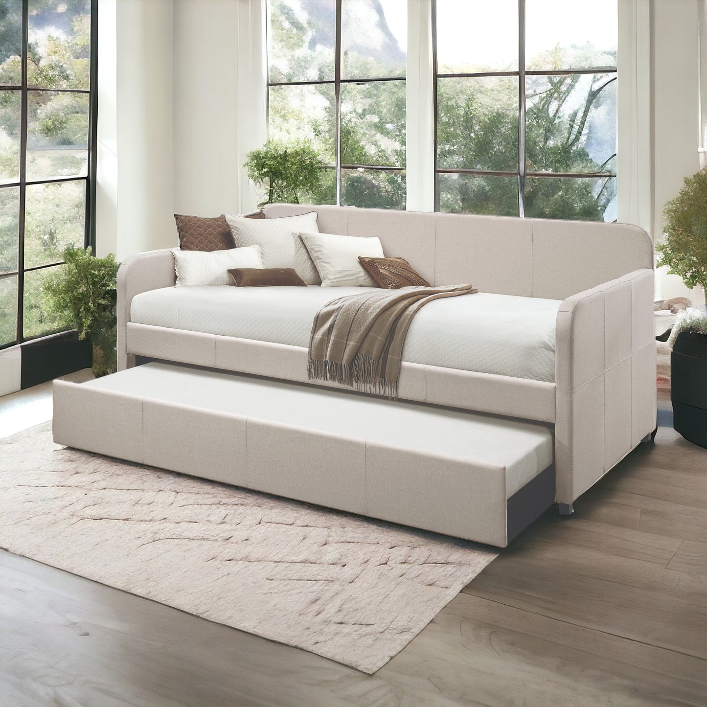 Beige upholstered daybed with pullout trundle featuring plush pillows and a woven throw