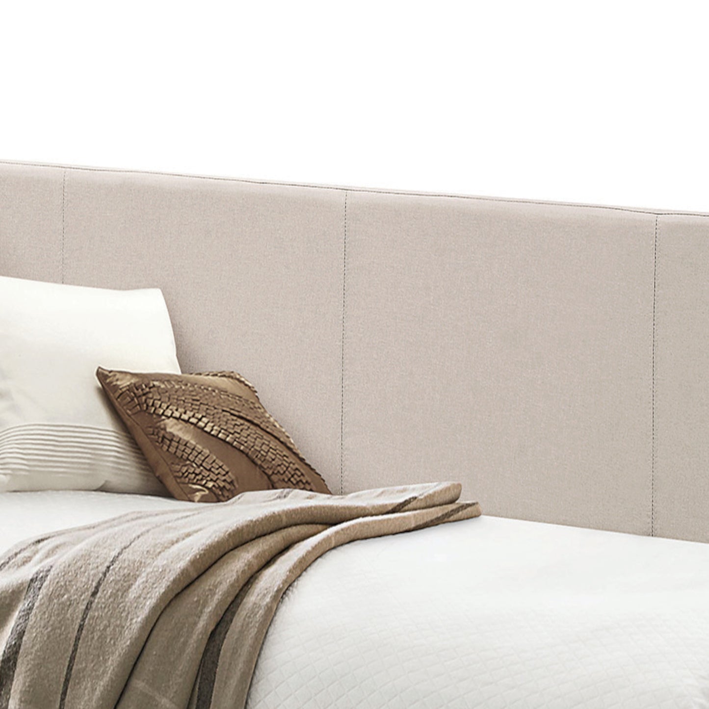 Beige upholstered headboard with neutral pillows and a textured throw blanket