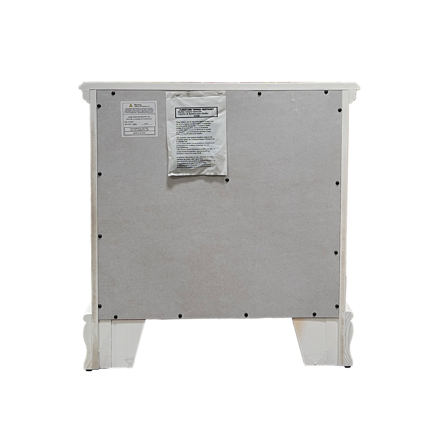 Back panel of a white distressed nightstand with ornate legs and two warning labels