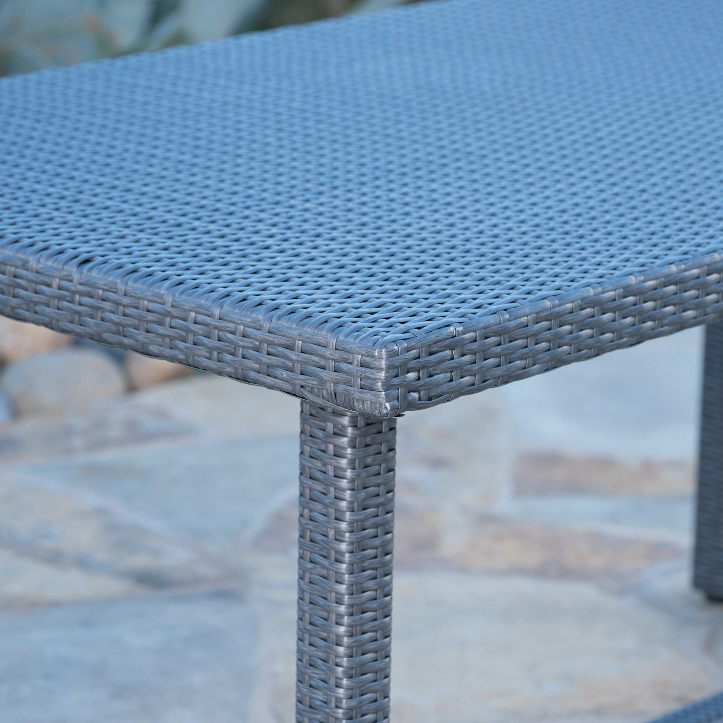 Closeup of a dark grey wicker coffee table corner with woven detail