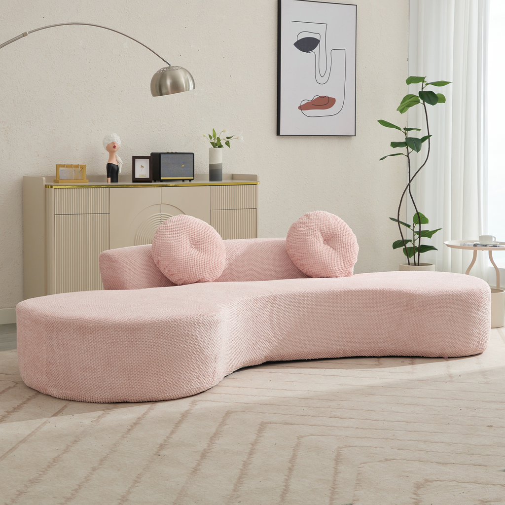 Curved blush pink sofa with textured fabric and matching round pillows perfect for modern living rooms