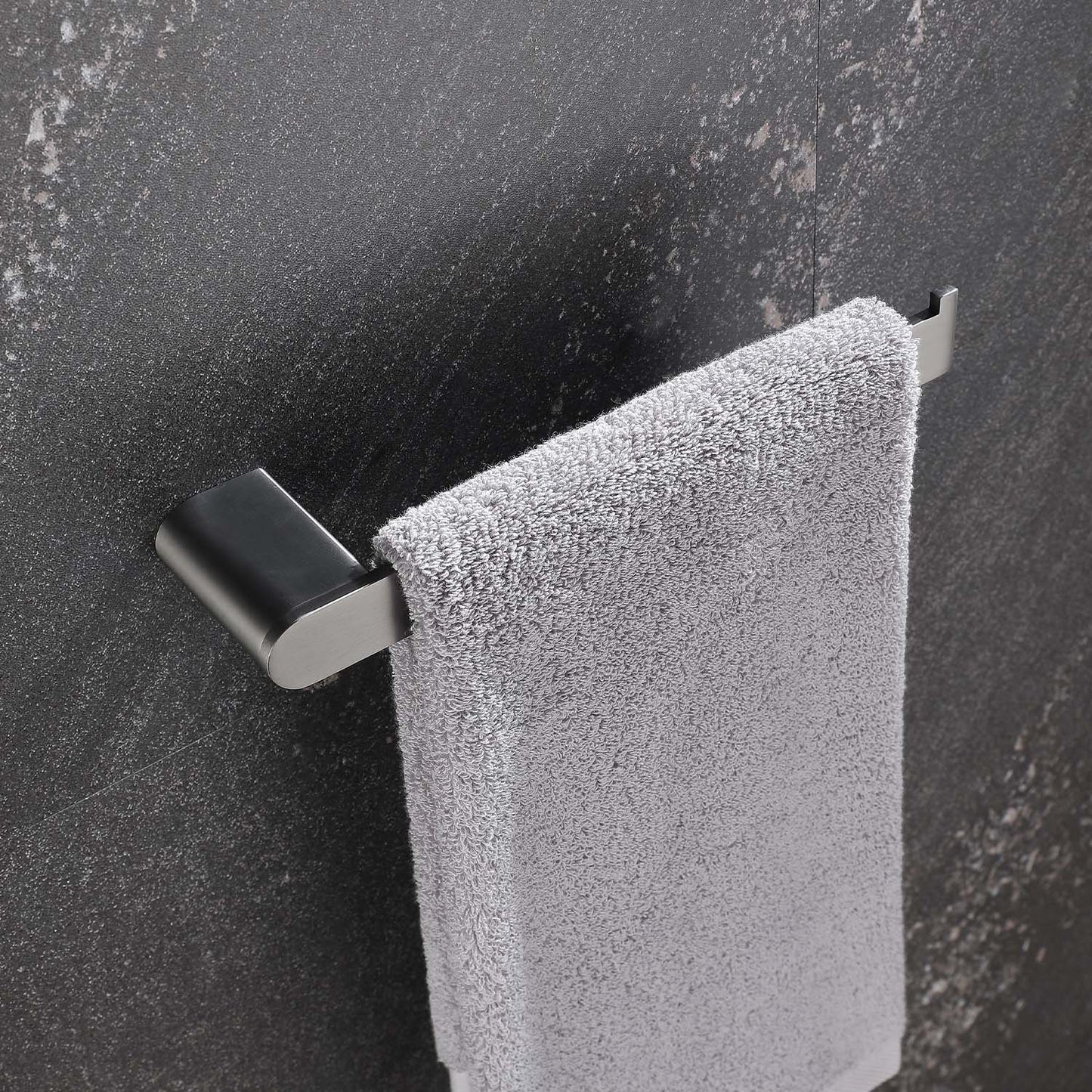 Brushed nickel towel bar holding a fluffy grey towel against a dark textured wall