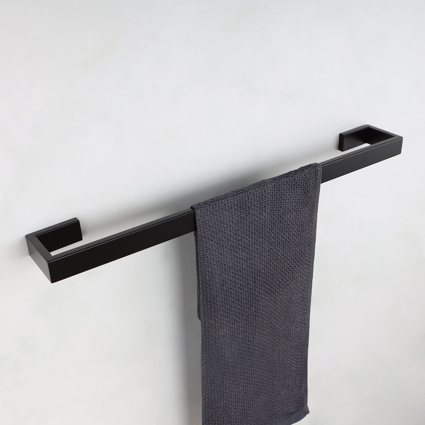 Modern black stainless steel towel bar with a textured charcoal gray hand towel