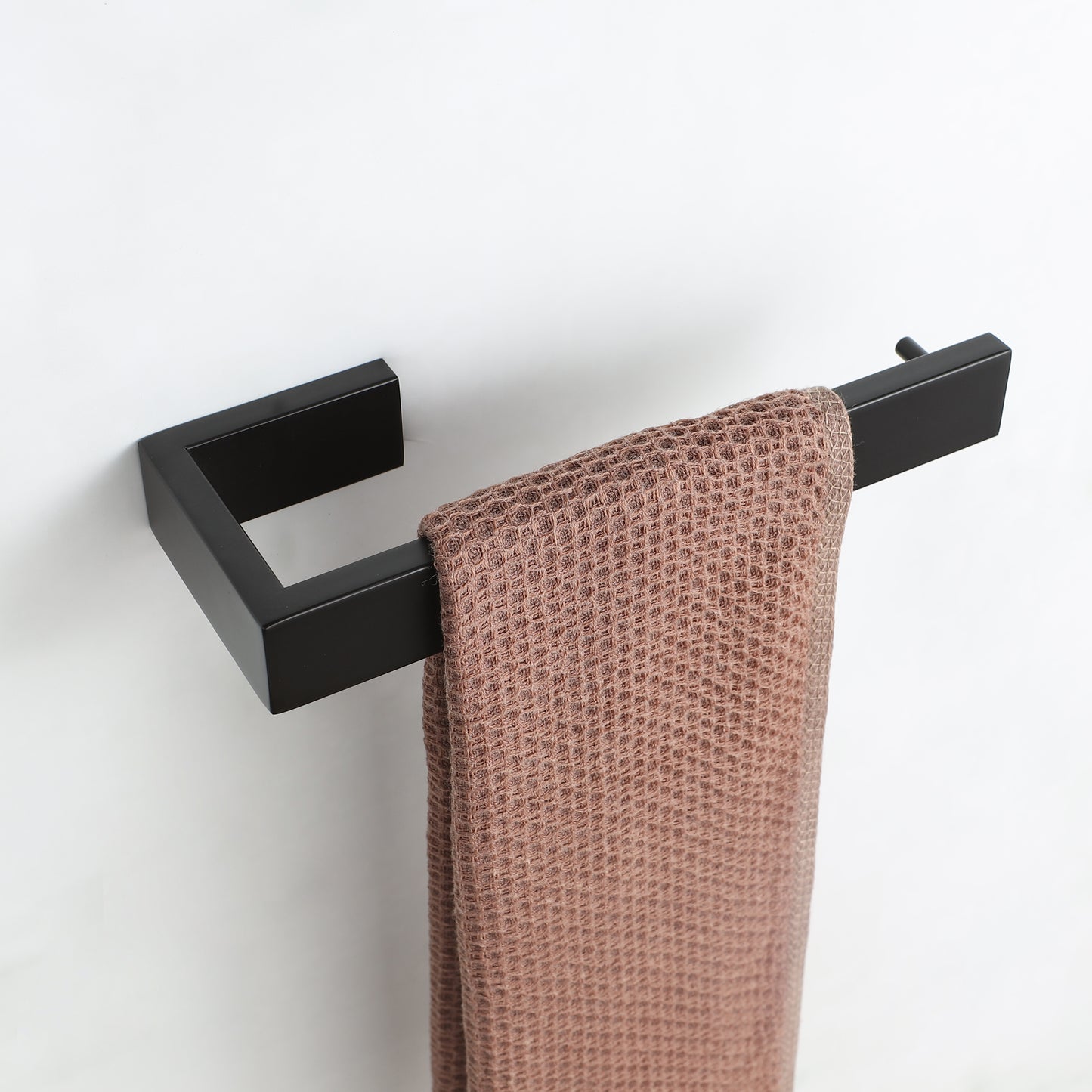 Modern black minimalist towel bar holding a textured blush pink hand towel for bathroom decor