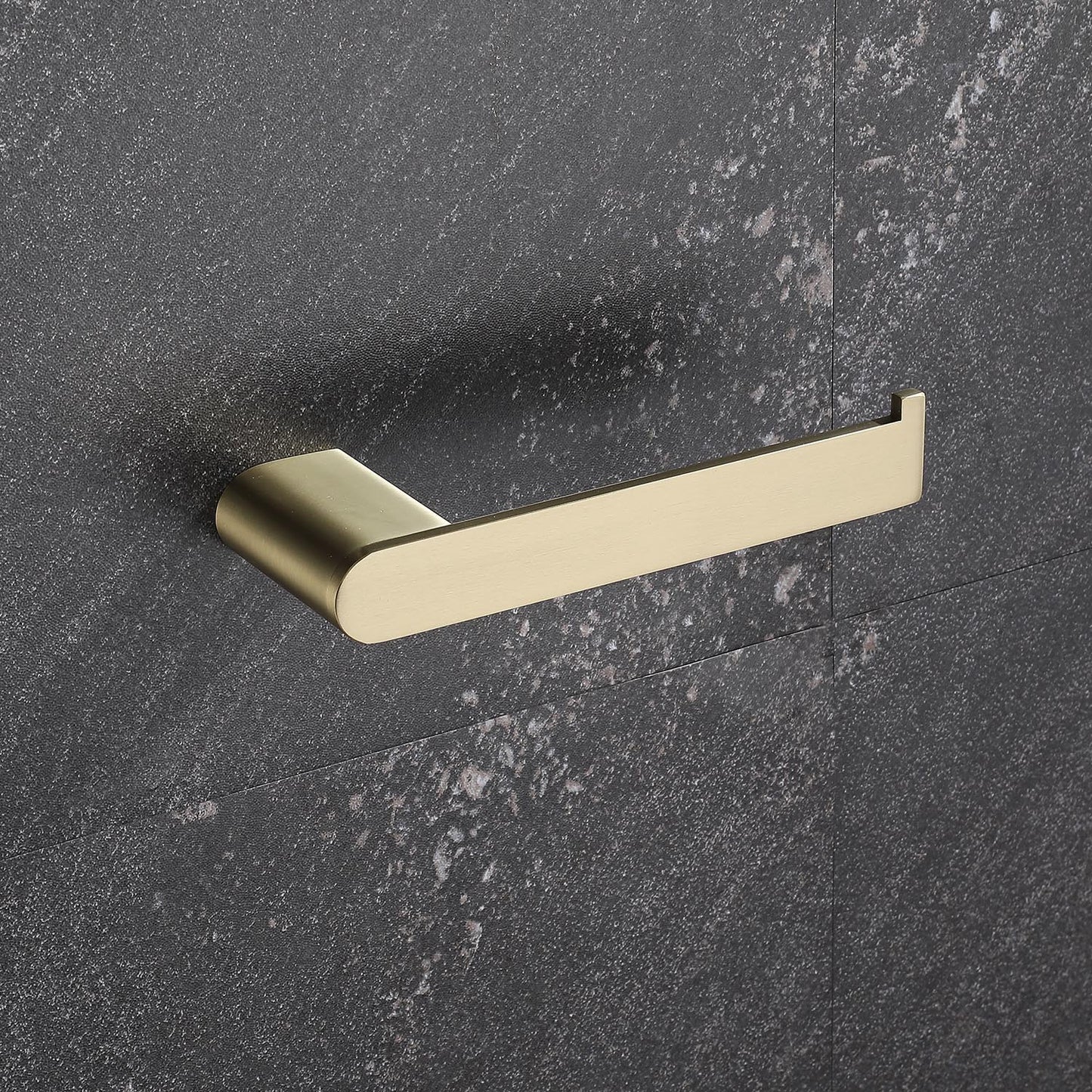 Brushed brass toilet paper holder mounted on a dark textured wall