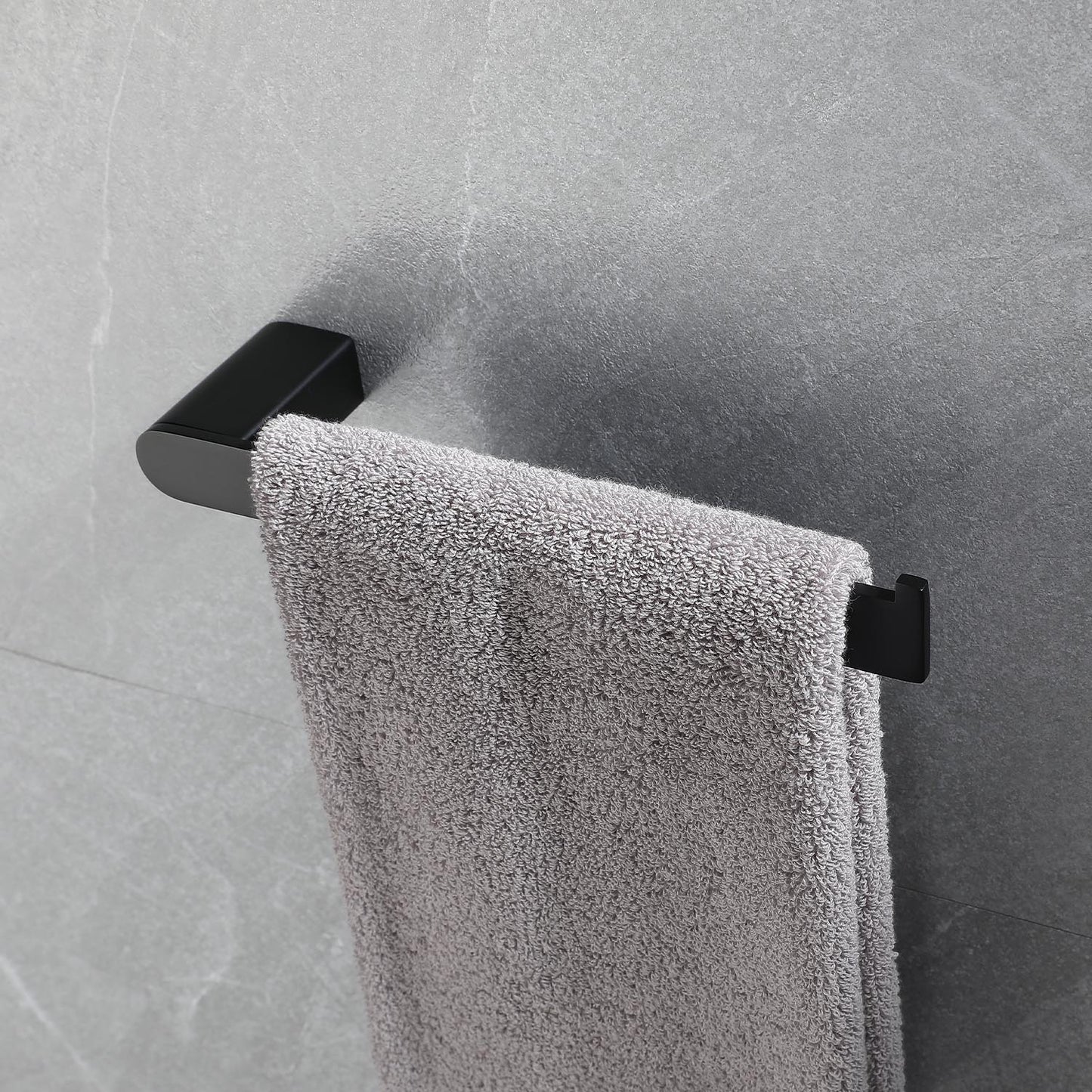 Sleek black single towel bar mounted on gray tiled wall holding a soft gray towel